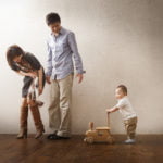 手押し車をおす１歳男の子と優しく見守る両親